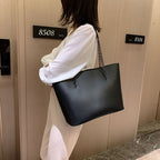 Sac à main noir femme en similicuir mat, porté épaule