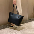 Sac à main noir femme en similicuir mat, porté épaule