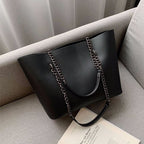 Sac à main noir femme en similicuir mat, porté épaule